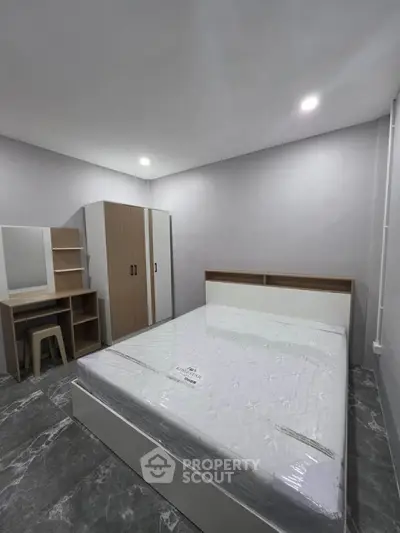 Modern bedroom with minimalist design featuring a bed, wardrobe, and study desk in a cozy setting.