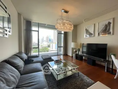 Luxurious living room with modern decor and city view, featuring a large sofa and elegant chandelier.