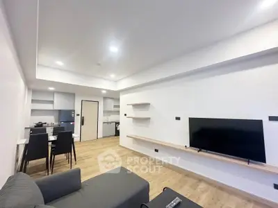 Modern living room with open kitchen, sleek furniture, and wooden flooring in a contemporary apartment.