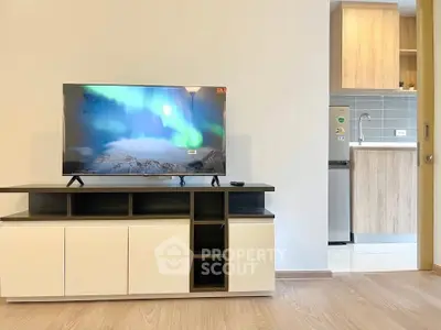 Modern living room with sleek TV stand and view into stylish kitchen area.