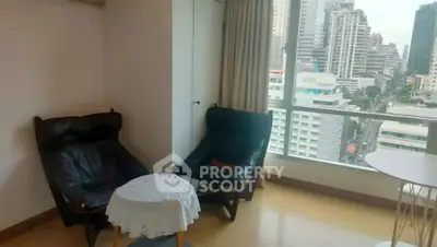 Cozy living room with city view, featuring two black armchairs and a small round table.