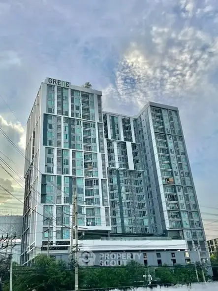 Modern high-rise building with sleek design and glass facade under a cloudy sky.