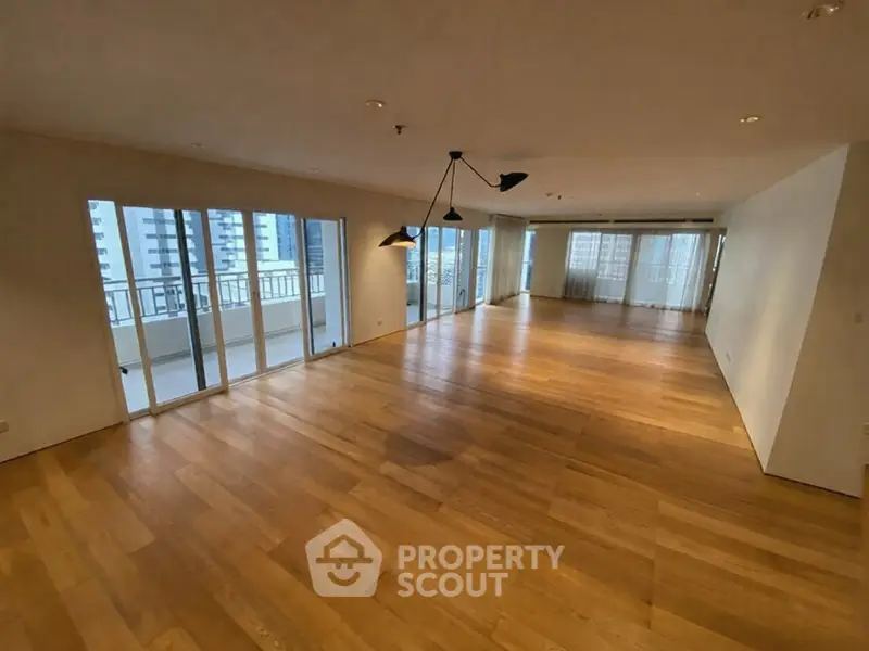 Spacious modern living room with wooden flooring and large balcony access.