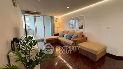 Spacious living room with cozy seating and modern decor, leading to a bright balcony area.