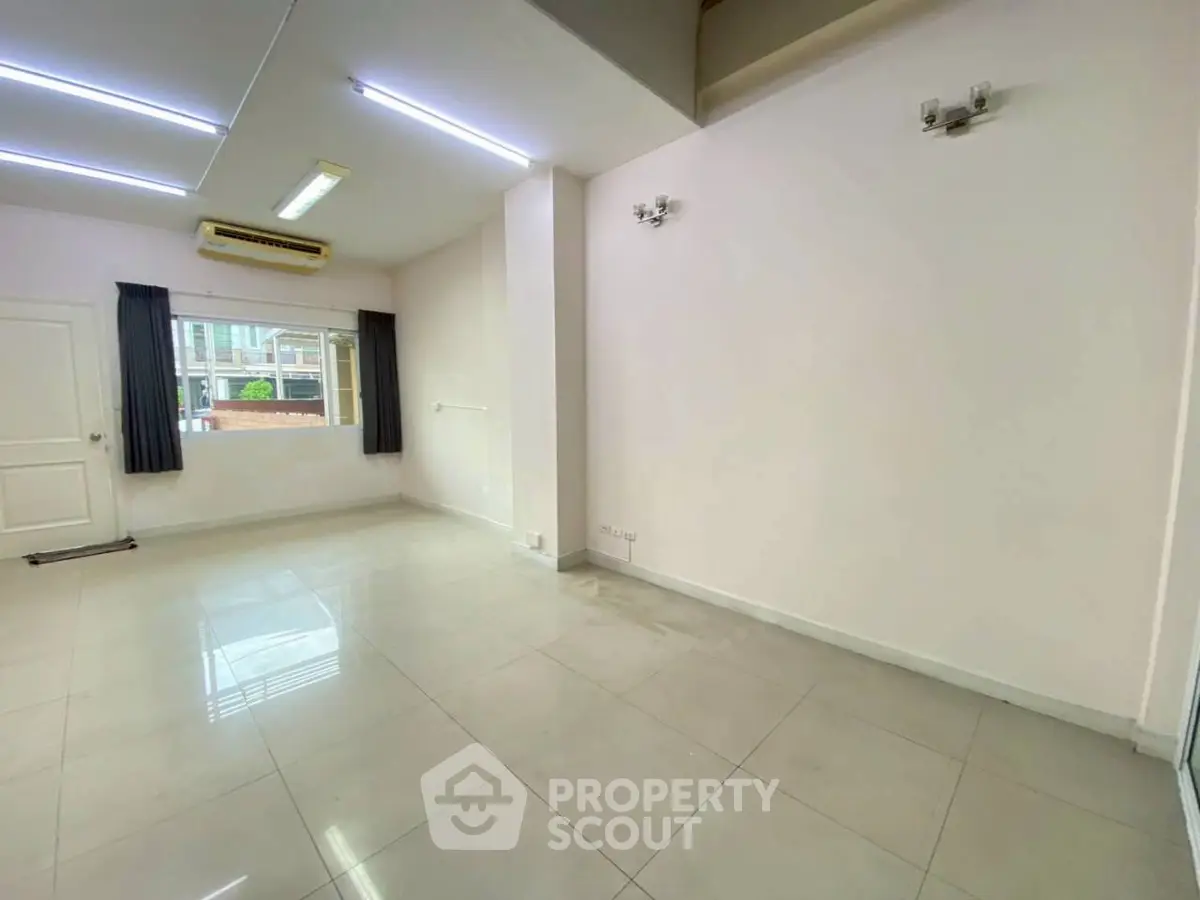 Spacious empty room with large window and tiled floor, ideal for customization.