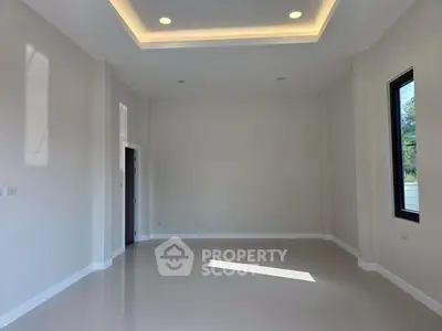 Spacious empty room with high ceiling and large window, perfect for customization.
