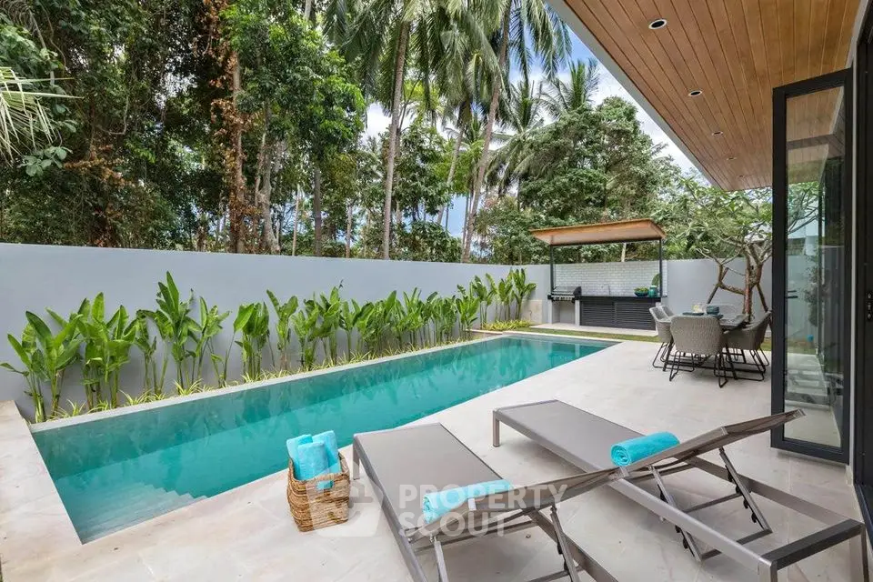 Luxurious tropical poolside retreat with lush greenery and modern outdoor seating area.