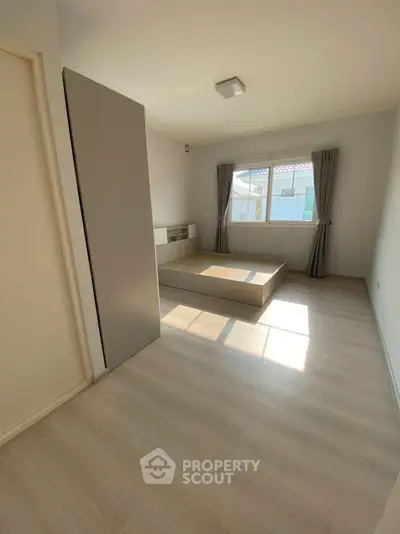 Spacious minimalist bedroom with large window and natural light