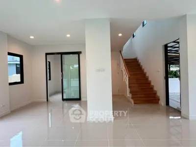 Spacious modern living area with sleek tile flooring and wooden staircase