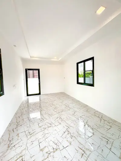 Spacious empty room with marble flooring and large windows, perfect for customization.
