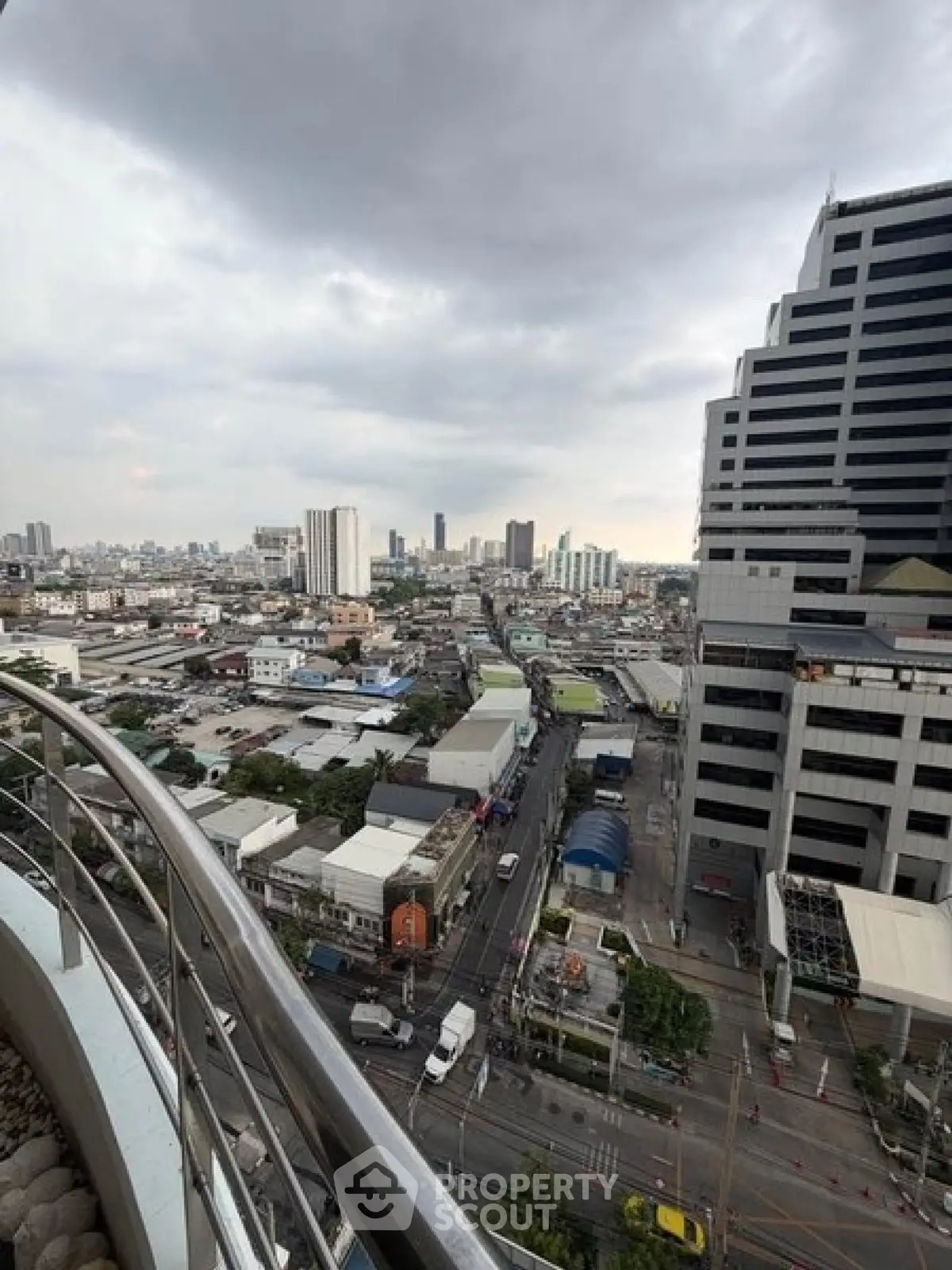 Stunning cityscape view from a high-rise balcony showcasing urban skyline and bustling streets.
