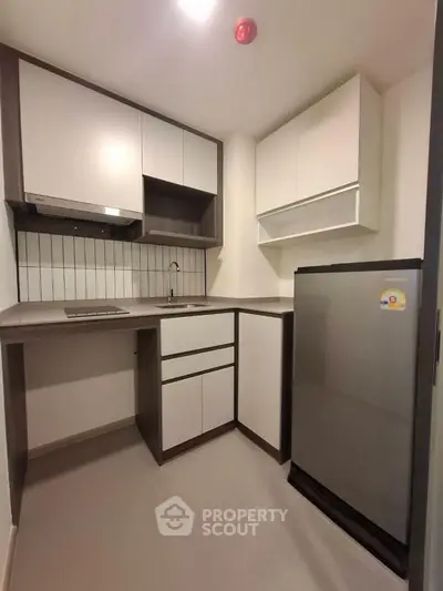 Modern compact kitchen with sleek cabinetry and stainless steel fridge