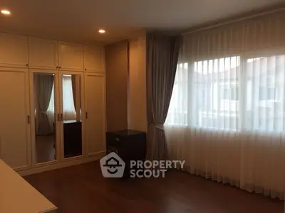 Spacious bedroom with large window and elegant curtains