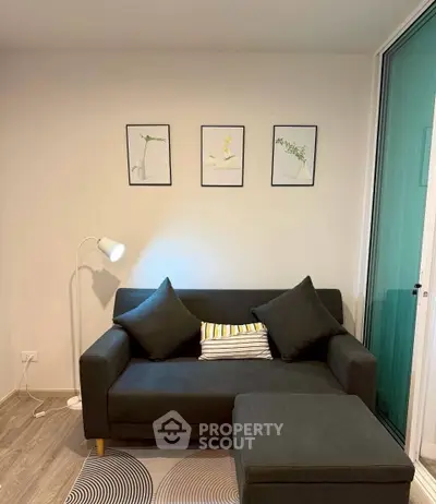 Modern living room with stylish sofa, floor lamp, and wall art in a cozy apartment setting.