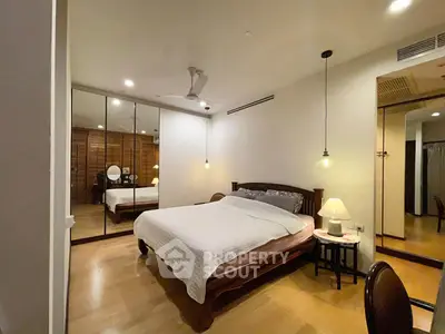 Spacious bedroom with mirrored closet and elegant wooden furniture