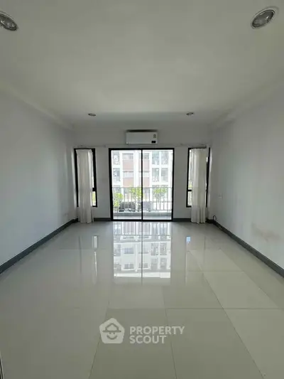 Spacious empty living room with large windows and city view, perfect for customization.