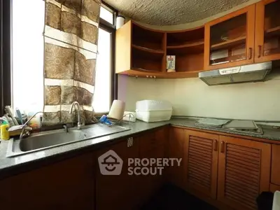 Cozy kitchen with wooden cabinets and large window, perfect for culinary enthusiasts.