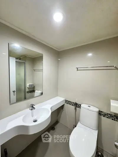 Modern bathroom with sleek fixtures and elegant design, featuring a spacious mirror and contemporary sink.