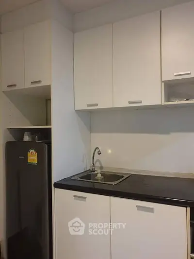 Modern kitchen with sleek cabinetry and compact fridge in minimalist design.