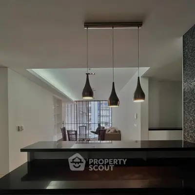 Modern open-plan living room with stylish pendant lights and sleek furniture.