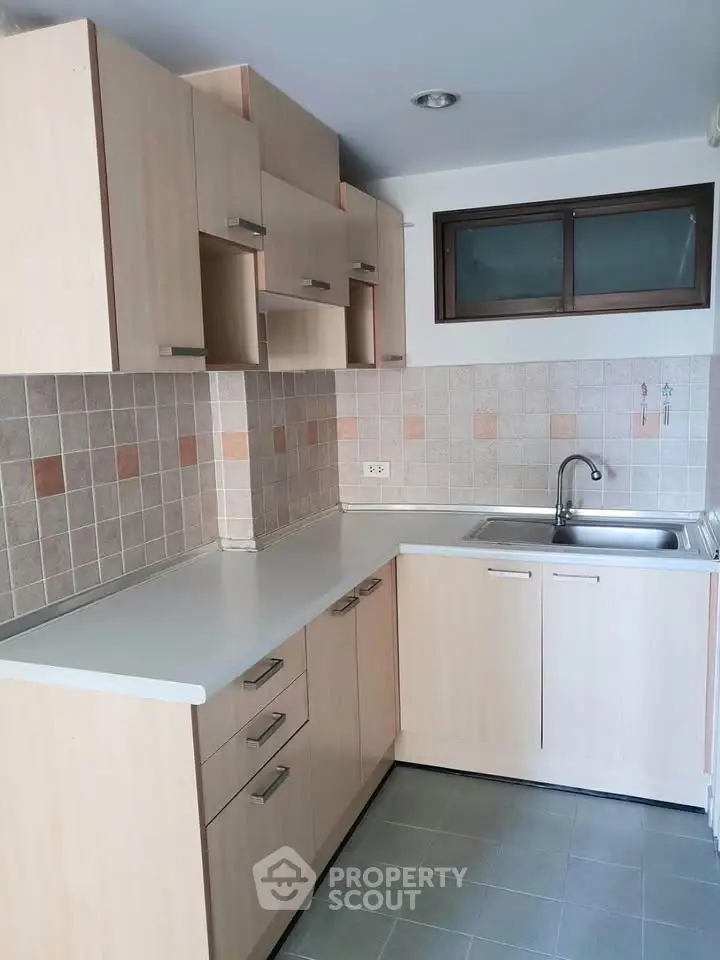 Modern kitchen with light wood cabinets and tiled backsplash