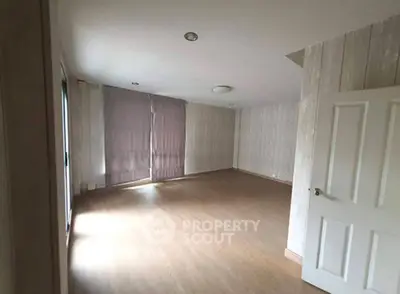 Spacious empty room with wooden flooring and large windows, ideal for customization.