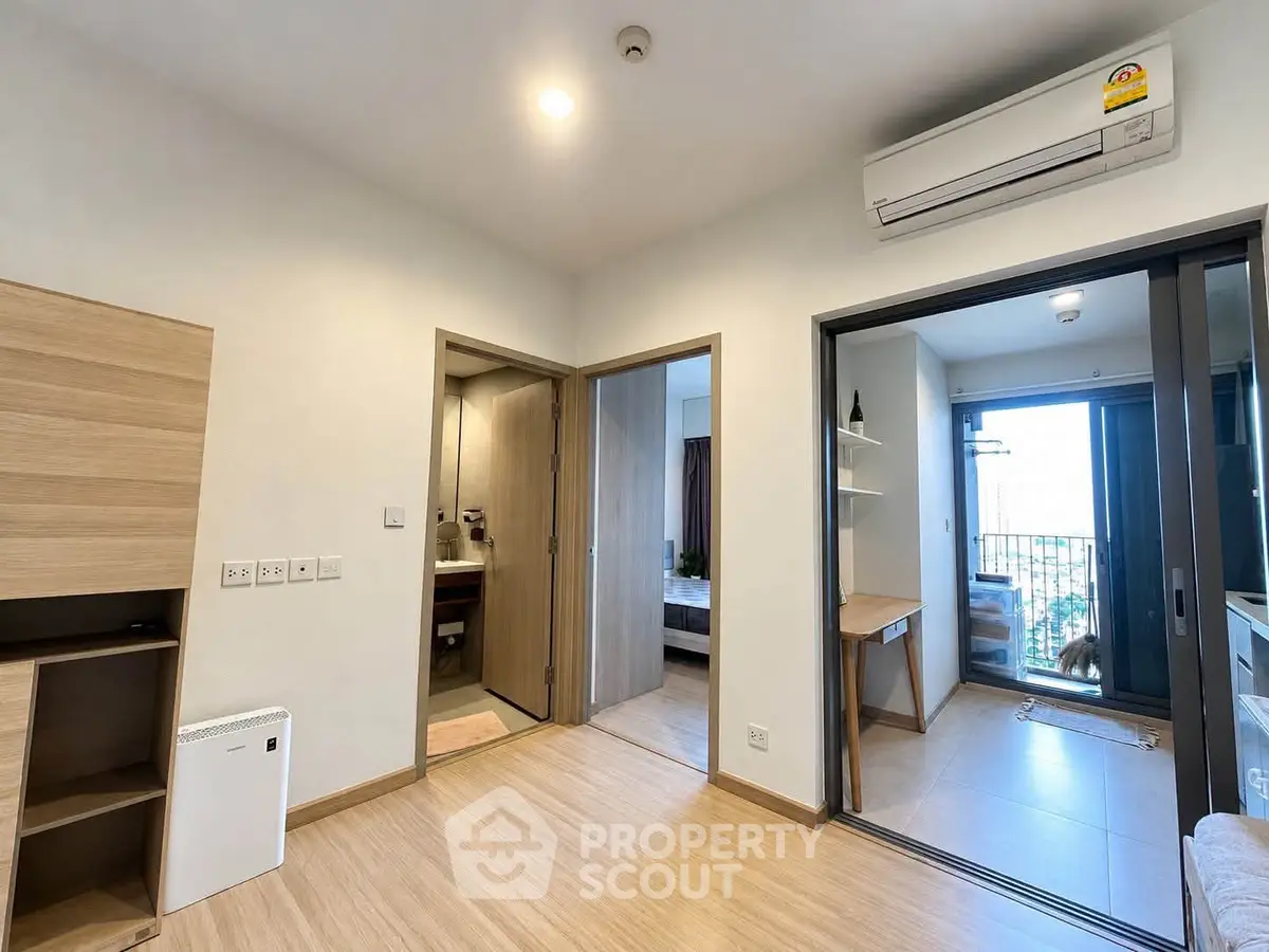 Modern apartment interior with wooden flooring, air conditioning, and balcony access, showcasing a cozy and functional living space.