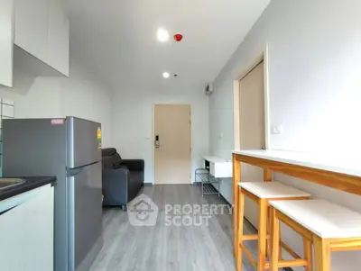 Modern apartment interior with sleek kitchen and cozy living area, featuring stylish bar stools and contemporary decor.