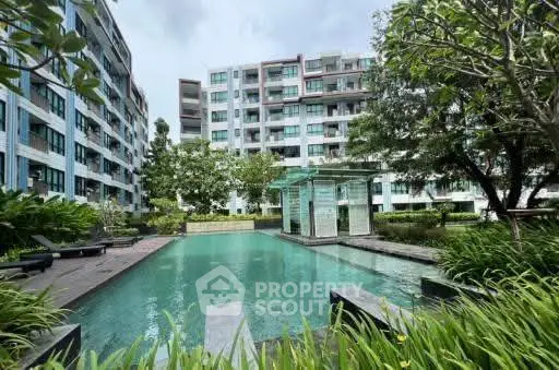 Modern apartment complex with lush greenery and inviting swimming pool.