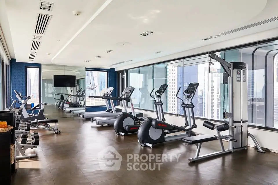 Modern gym with city view and state-of-the-art equipment in luxury building.