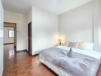 Spacious bedroom with cozy decor and wooden flooring in modern apartment.