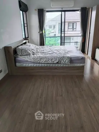 Spacious bedroom with large window and wooden flooring in modern home