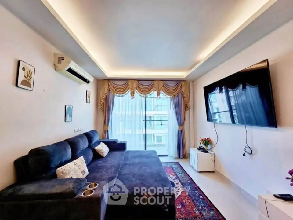 Modern living room with large sofa, wall-mounted TV, and elegant curtains.