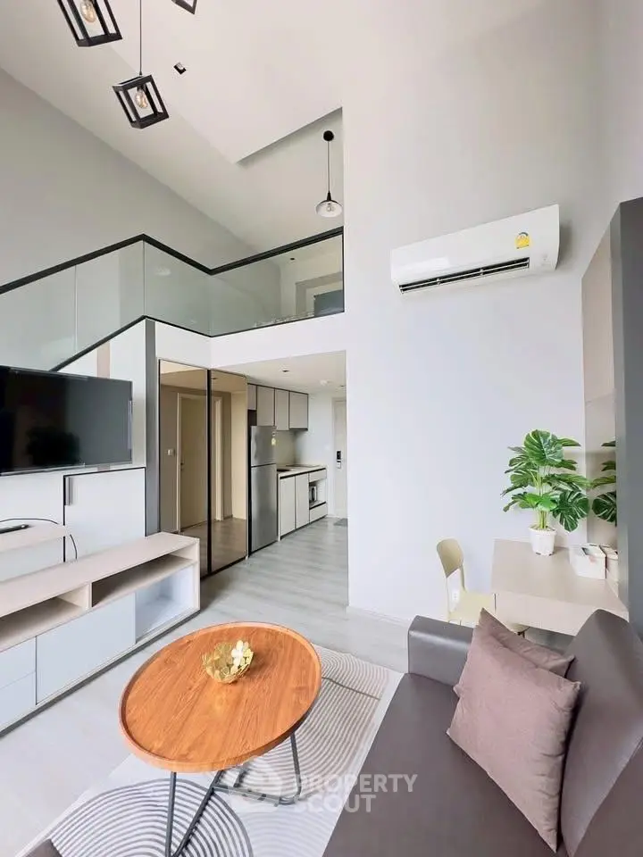 Modern living room with loft design, featuring sleek furniture and open kitchen layout.