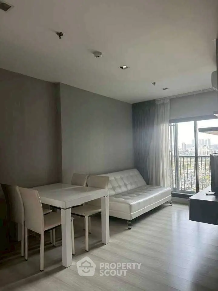 Modern living room with sleek furniture and city view balcony.