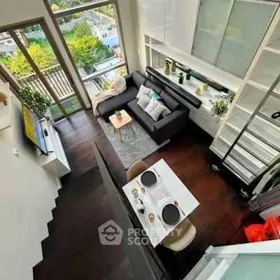 Modern loft apartment with high ceilings, large windows, and stylish living area overlooking cityscape.