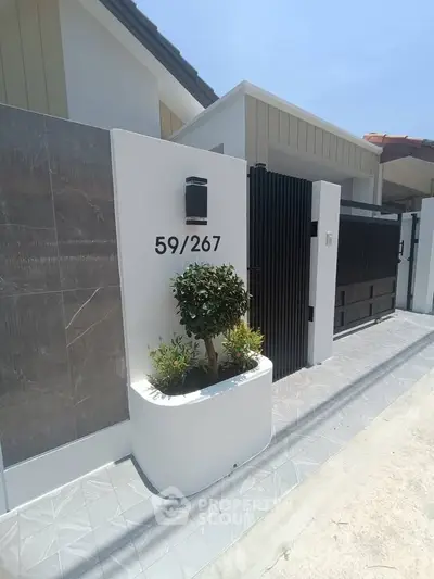 Modern house exterior with sleek gate and stylish address display, showcasing contemporary architectural design.