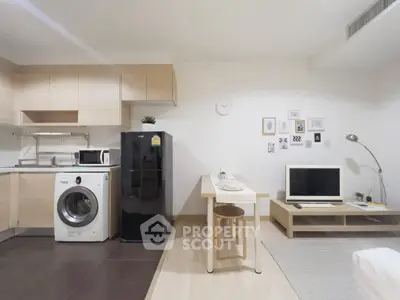 Modern studio apartment with open kitchen, washing machine, and cozy living area.