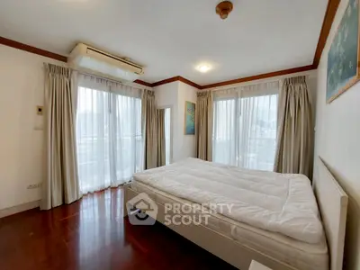 Spacious bedroom with large windows and elegant curtains in a modern apartment.