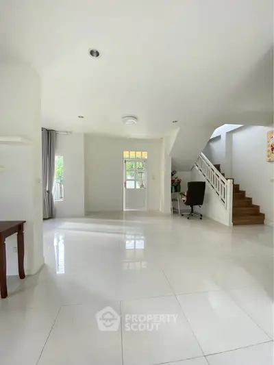Spacious modern living room with bright natural light and elegant staircase