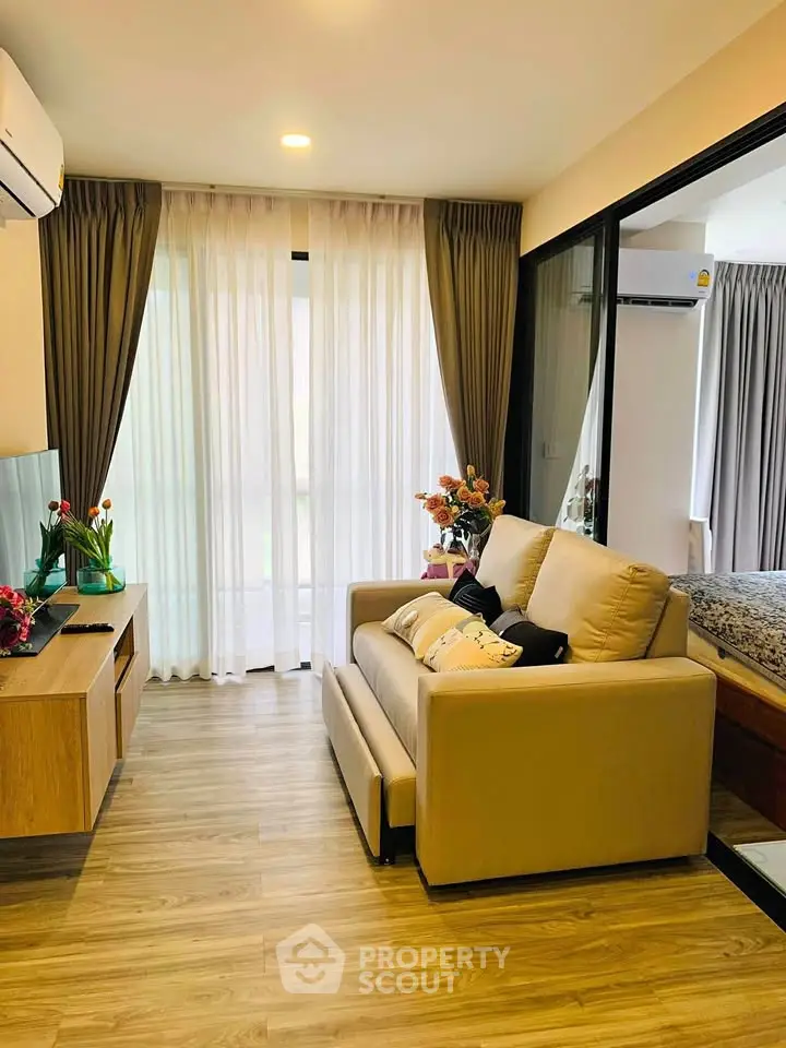 Modern living room with cozy sofa, wooden flooring, and large window with curtains in a stylish apartment.