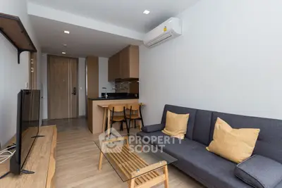 Modern living room with sleek furniture and open kitchen layout, featuring a cozy sofa and stylish decor.