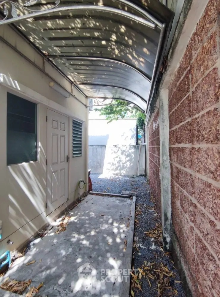 Charming side alley with covered walkway and brick wall, perfect for outdoor storage or garden space.