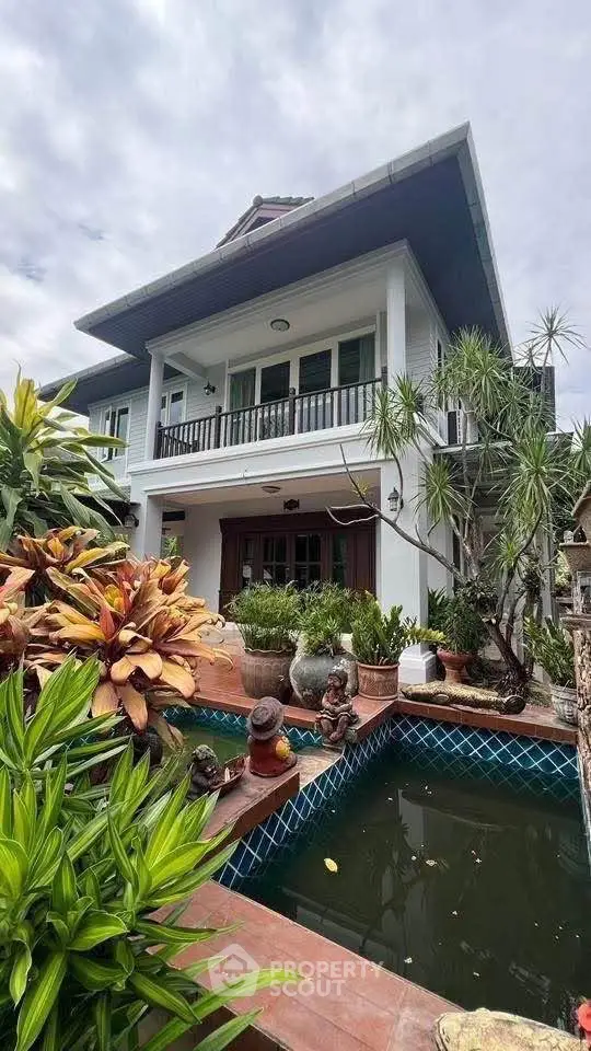 Charming two-story house with lush garden and decorative pond, perfect for serene living.