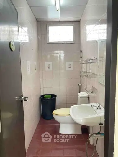 Compact bathroom with tiled walls and basic fixtures, ideal for small spaces.