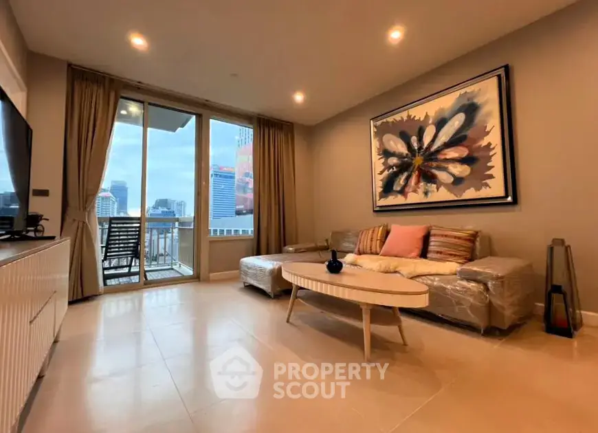 Spacious living room with modern decor and city view balcony in high-rise apartment.