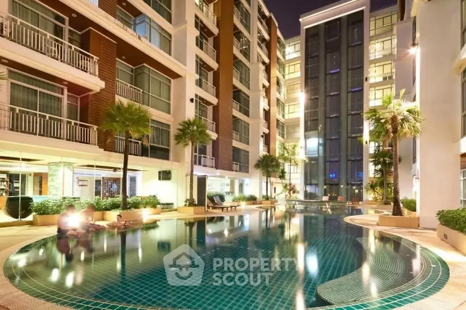 Luxurious apartment complex with illuminated pool and modern architecture at night.