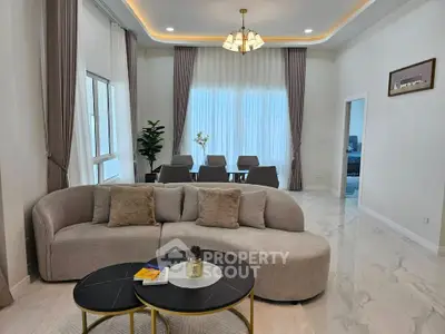 Elegant living room with modern furniture and dining area, featuring large windows and stylish decor.