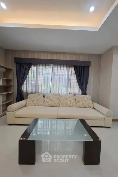 Spacious living room with elegant sofa and modern glass coffee table, perfect for relaxation and entertaining.
