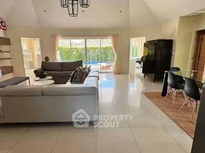 Spacious living room with modern decor and pool view, perfect for family gatherings.